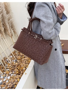 Detail of vintage leopard print tote bag with metal buckle on an autumn outdoor background