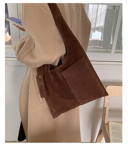 Close-up of dark brown suede tote bag with front pocket and silver metal buckle detail