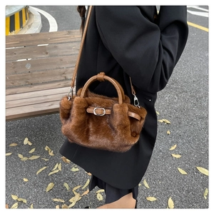 Détail d'un sac à main en peluche avec poignées en cuir porté par un mannequin en automne