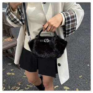 Vue détaillée d'un sac à main noir en fausse fourrure avec poignées tressées et boucles