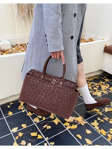Macro detail of large leopard print tote bag with metal buckle strap on autumn street