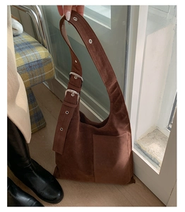 Detail of the brown suede shoulder bag showing adjustable straps and smooth texture