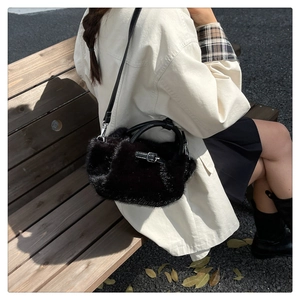 Sac à bandoulière en fausse fourrure noire avec boucle argentée sur un banc de parc