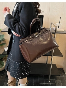 Detailed view of chocolate brown glossy leather tote bag with metal buckle and top handles