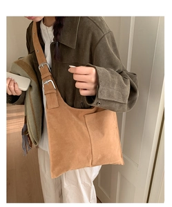 Detail of a brown suede crossbody bag with wide adjustable shoulder straps and silver buckles