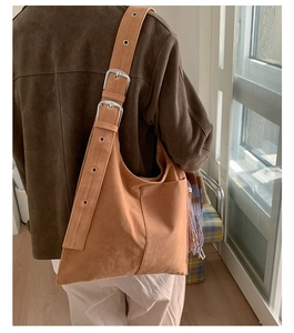Close-up of brown suede shoulder bag with retro metal buckle strap and matte texture