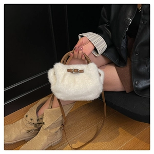 Détail d'un sac à main blanc en peluche avec poignées en cuir marron et bandoulière