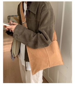 Detail of camel suede shoulder bag showing adjustable strap and silver metal buckle
