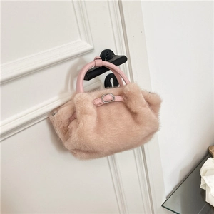 Détail d'un sac à main en fausse fourrure rose montrant la texture douce et la boucle