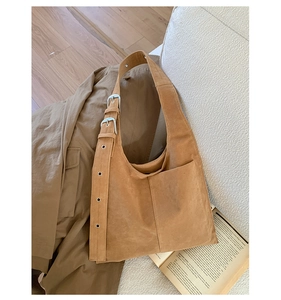 Close-up of brown suede tote bag with double buckle straps and metallic eyelets