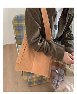 Detail of a large brown suede tote bag featuring metallic eyelets and a wide shoulder strap