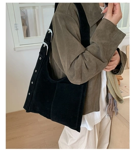 Detail showing the black faux suede texture and silver adjustable buckles on the shoulder strap
