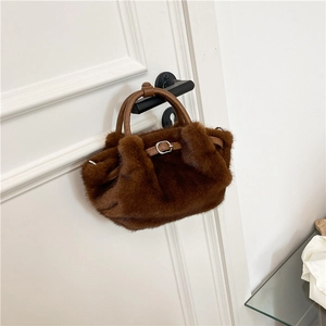 Détail d'un sac à main en peluche marron foncé avec fausse fourrure et anse en cuir