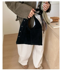 Detail of black faux suede underarm bag with silver metal eyelet and soft texture