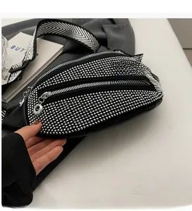 Detail of a black crossbody bag with silver studs and multi-zipper compartments