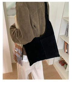 Close-up of black suede tote bag with front pocket styled for autumn winter commute