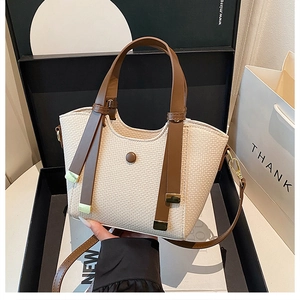 Detail of woven fabric handbag with brown leather trim and metallic buckle closure