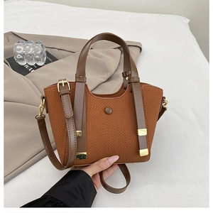 Close-up of caramel brown waffle texture bag with leather straps on white bedding