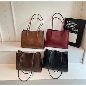 Close-up of four minimalist leather tote bags in brown, burgundy and black colors