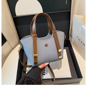 Detail of blue woven texture handbag with brown leather strap in a premium gift box