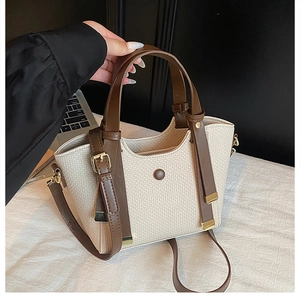 Detail of beige woven handbag with brown leather straps and polished gold hardware