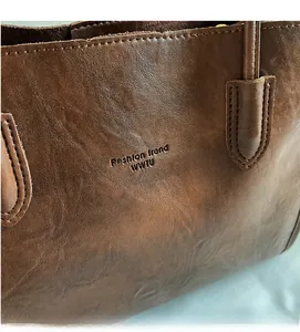 Close-up of deep brown tote bag with embossed fashion logo and smooth leather texture