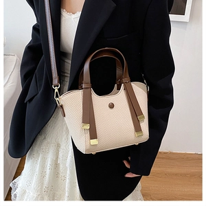 Close-up of woven bucket bag with leather trim and adjustable shoulder strap for women