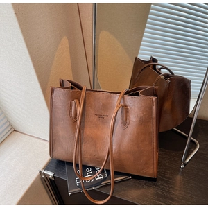 Detail of vintage brown PU leather tote bag with Fashion trend text on a dark surface