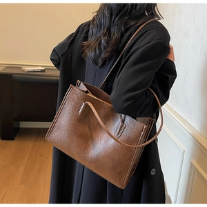 Detail view of vintage brown PU leather tote bag with fine textures and long strap