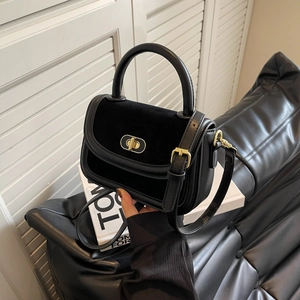 Elegante borsa a tracolla in pelle nera e velluto con chiusura dorata su divano