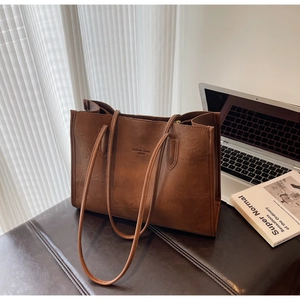 Detail of dark brown leather tote bag with Fashion trend WWJU logo in office setting