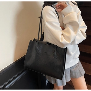 Detail of vintage black PU leather tote bag with Forever Young embossed text on the side