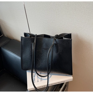 Detailed view of black faux leather tote bag with embossed fashion trend logo lettering