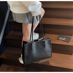 Detail of vintage black PU leather tote with gold zipper and textured finish
