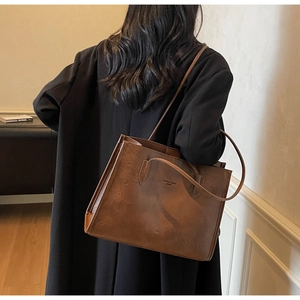 Detail of vintage brown PU leather tote bag with Fashion Trend embossed text on front