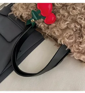 Close-up of plush brown faux fur tote bag with leather handle and red cherry charm