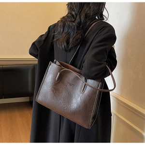 Close-up of vintage brown PU leather tote bag showing textured surface and side profile