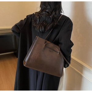 Close-up of dark brown vintage leather tote bag featuring a Fashion trend embossed logo