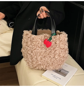 Detail of plush beige faux fur tote bag with leather handle and red cherry charm