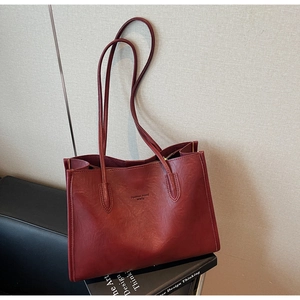Detail of burgundy PU leather tote bag showing fine texture and embossed fashion text