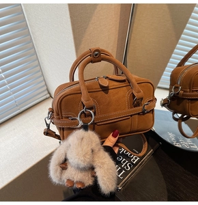 Brown faux suede rectangular bag featuring a cute plush bunny charm and golden hardware