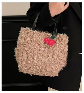 Dettaglio della borsa beige in shearling con manico nero e ciondolo a ciliegia rosso