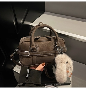 Close-up of brown Boston bag with white stitching and a cute plush rabbit charm