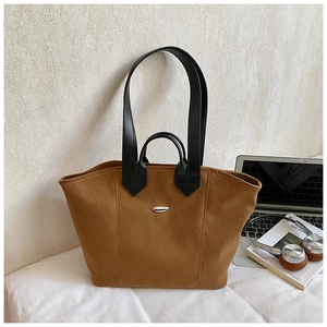 Detailaufnahme einer karamellfarbenen Tote Bag mit schwarzen Riemen und Silberschnalle