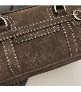 Close-up of retro brown pillow bag showing litchi grain texture and contrast stitching