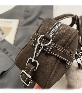 Close-up of dark brown matte leather handbag featuring contrast white stitching and silver hardware