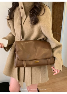 Nahaufnahme einer braunen Retro-Ledertasche kombiniert mit einem beigen Wollmantel