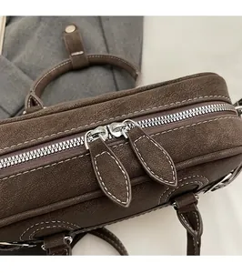 Detailed close-up of brown vintage hobo bag with silver double zippers and white stitching