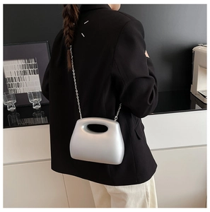 Silver frosted acrylic clutch bag with cutout handle and chain strap on a black blazer