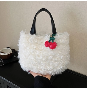 Dettaglio borsa in peluche bianca con manici in pelle nera e ciondolo a forma di ciliegia
